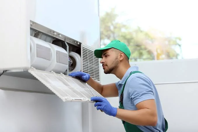 Stock photo of a technician cleaning the filter area of an indoor unit