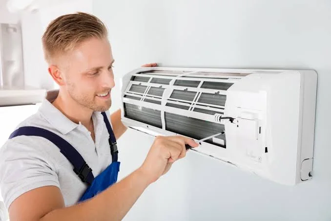 Stock photo of a technician repairing an outdoor condenser